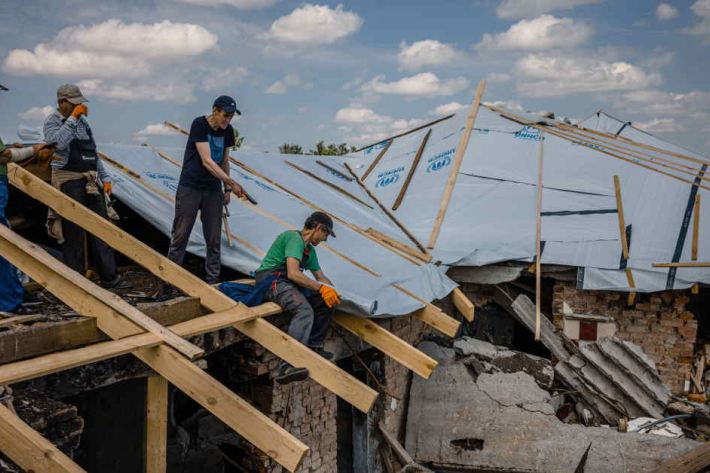 Workers repair a roof in Makariv