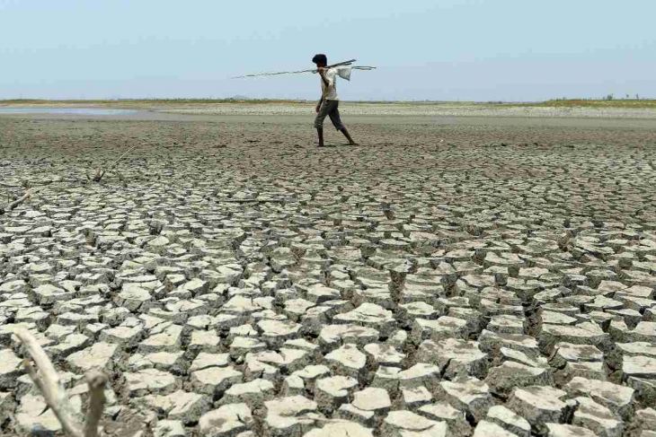 An Indian man walks over the parched bed of a reservoir on the outskirts of Chennai on 17 May 2017