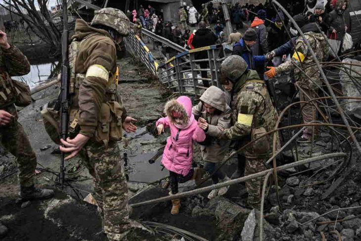 People crossing a destroyed bridge in Ukraine