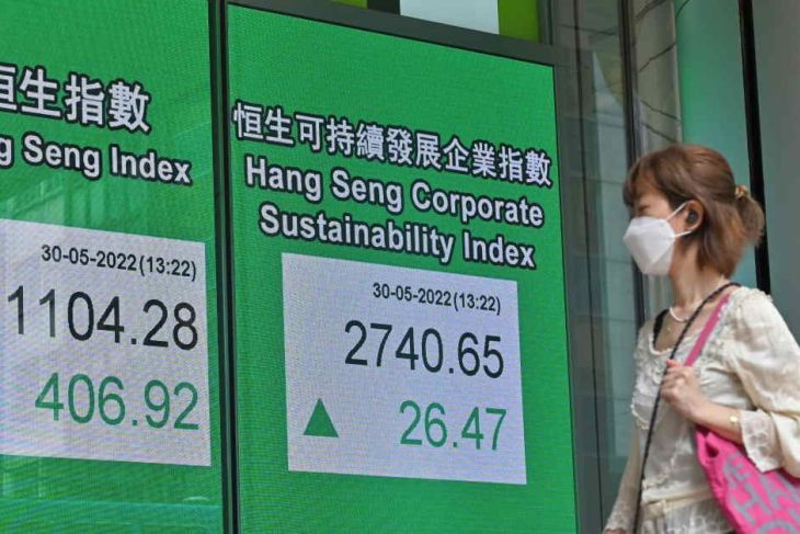 Woman walking in front of Hang Seng shares notice board