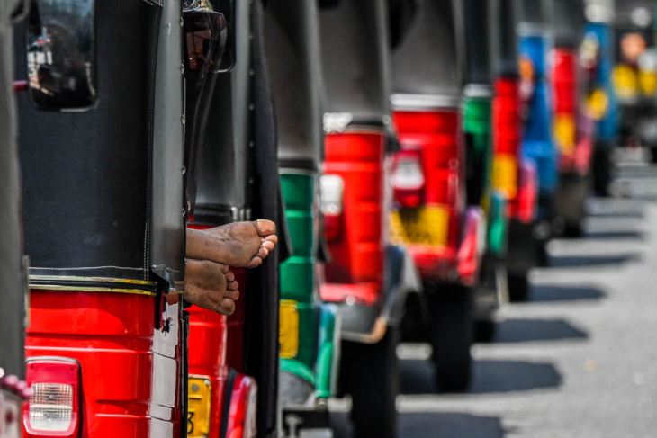 Autorickshaws are parked in a queue along a street to tank up petrol in Colombo