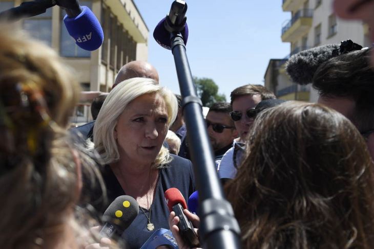 Marine Le Pen (C) answers journalists' questions during a campaign visit