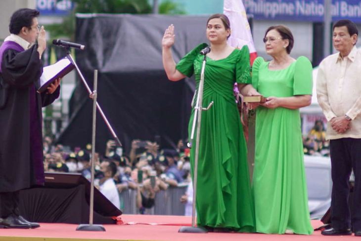 Philippines' Vice President-elect Sara Duterte (C) takes her oath before supreme court associate justice Ramon Hernando 