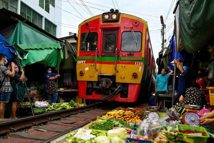 A train passes through the railway market at Samut Songkhram